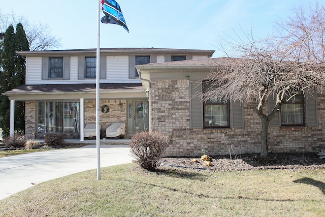 view of front of property featuring brick siding, a porch, concrete driveway, and a front lawn