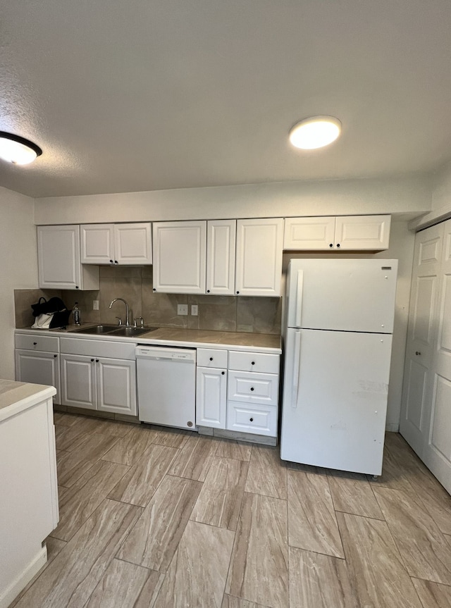 kitchen with a sink, decorative backsplash, white appliances, and white cabinetry