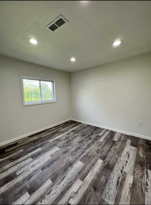 empty room featuring dark wood finished floors, recessed lighting, baseboards, and visible vents