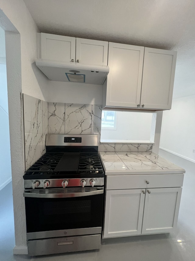 kitchen featuring stainless steel gas range oven, decorative backsplash, under cabinet range hood, and white cabinets