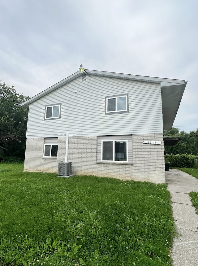 view of side of property with brick siding, central air condition unit, and a yard