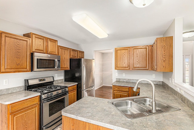 kitchen featuring a sink, a peninsula, light countertops, and stainless steel appliances