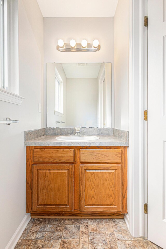 bathroom featuring vanity, stone finish floor, and baseboards