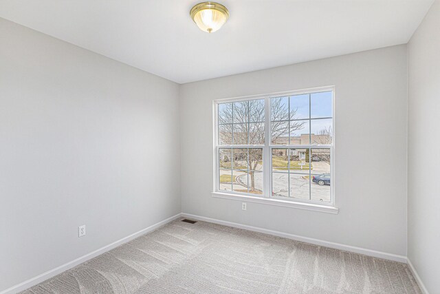 unfurnished room featuring visible vents, light colored carpet, and baseboards