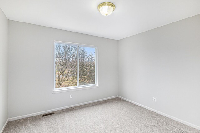 carpeted spare room featuring visible vents and baseboards