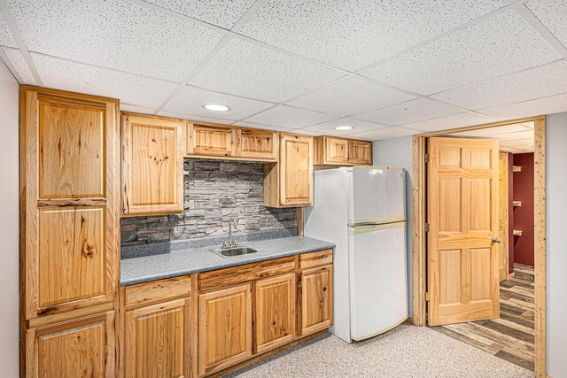 kitchen featuring tasteful backsplash, recessed lighting, freestanding refrigerator, a paneled ceiling, and a sink