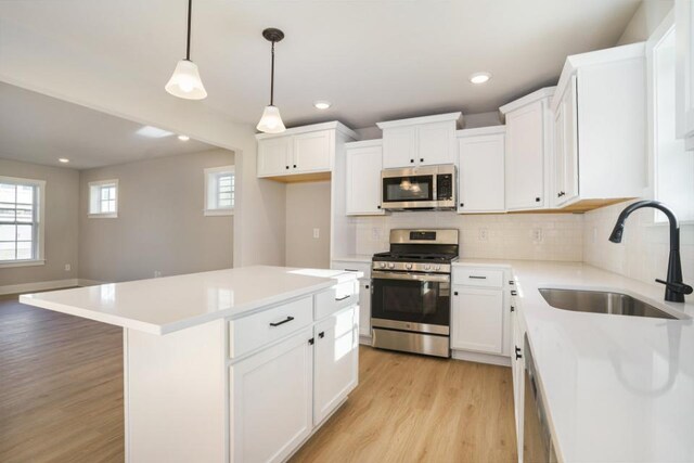 kitchen with tasteful backsplash, stainless steel appliances, light wood-style floors, white cabinetry, and a sink