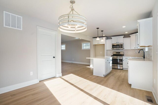 kitchen with tasteful backsplash, visible vents, light wood-style floors, stainless steel appliances, and a sink