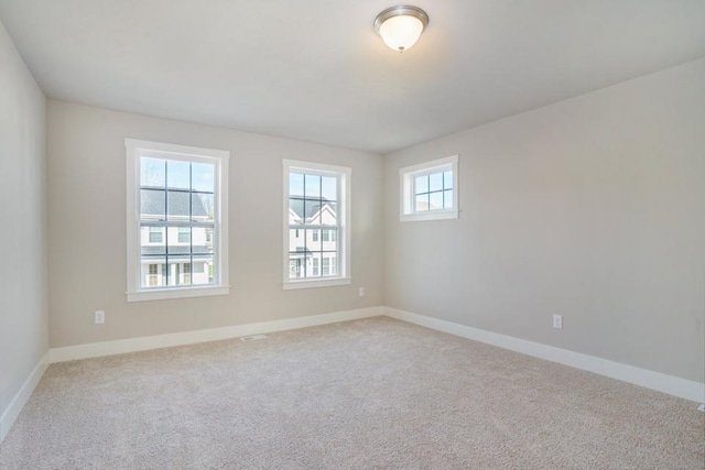 unfurnished room featuring baseboards and light colored carpet