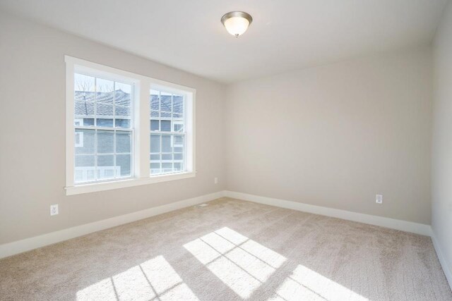 spare room with light carpet and baseboards