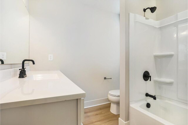 bathroom featuring toilet, wood finished floors, baseboards, bathtub / shower combination, and vanity