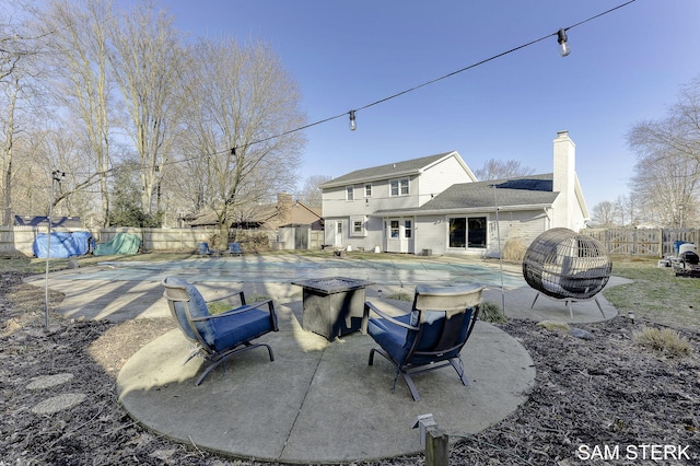 rear view of property with a patio area, a fenced backyard, a fenced in pool, and a chimney