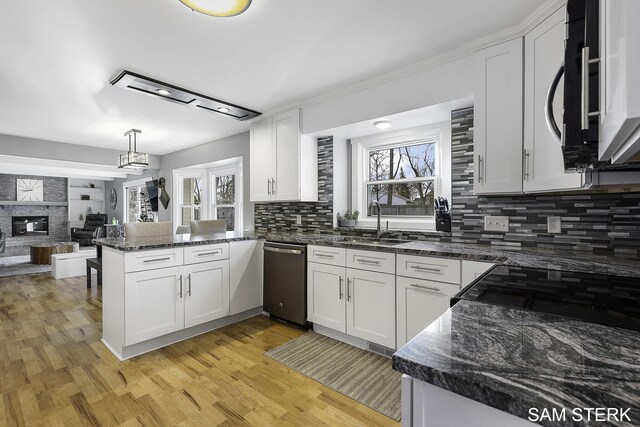 kitchen featuring plenty of natural light, a peninsula, white cabinets, and a fireplace