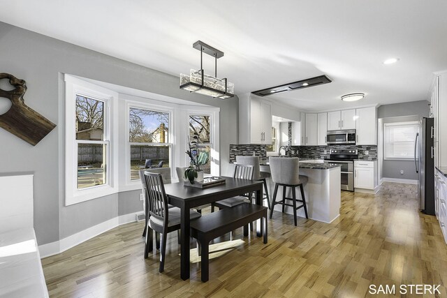 dining room with recessed lighting, light wood-style floors, and baseboards