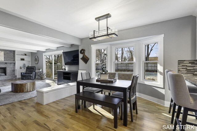 dining room featuring a chandelier, baseboards, light wood-style flooring, and a fireplace