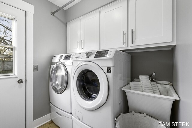 clothes washing area featuring light wood-type flooring, washer and dryer, a sink, cabinet space, and baseboards