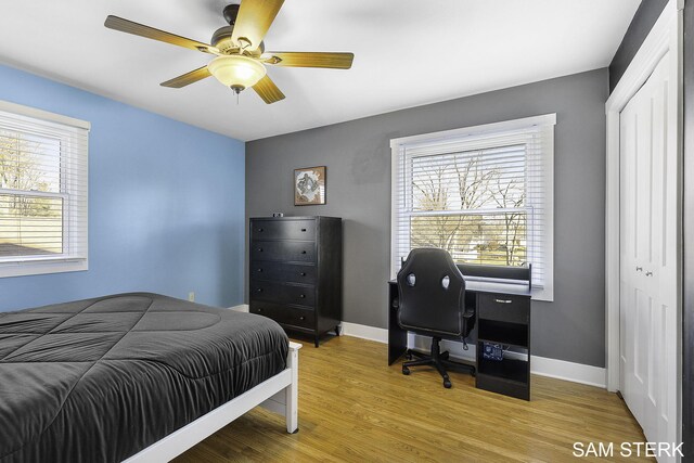 bedroom featuring a closet, baseboards, wood finished floors, and a ceiling fan