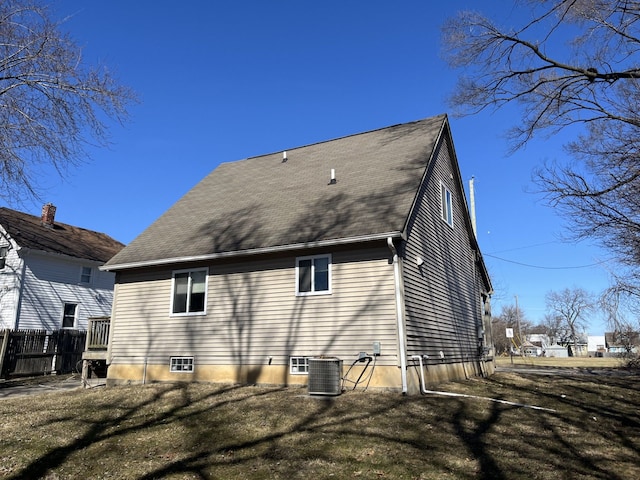 back of property featuring central air condition unit, a lawn, and fence