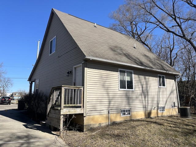 rear view of house with central AC and a shingled roof