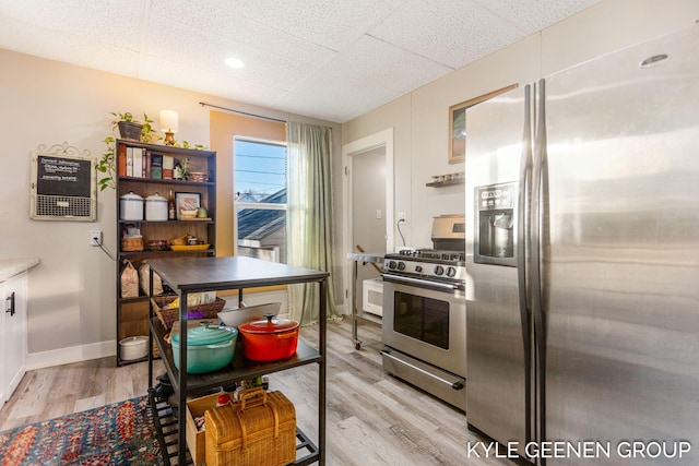 kitchen with a paneled ceiling, stainless steel appliances, baseboards, and light wood finished floors