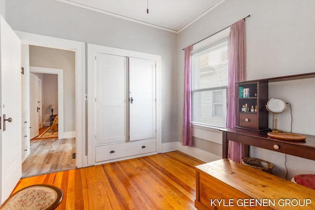 interior space with light wood-style flooring, baseboards, and ornamental molding