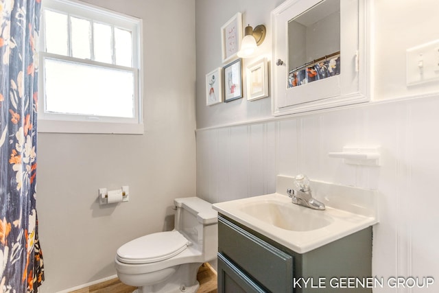 full bathroom with vanity, toilet, and a wainscoted wall