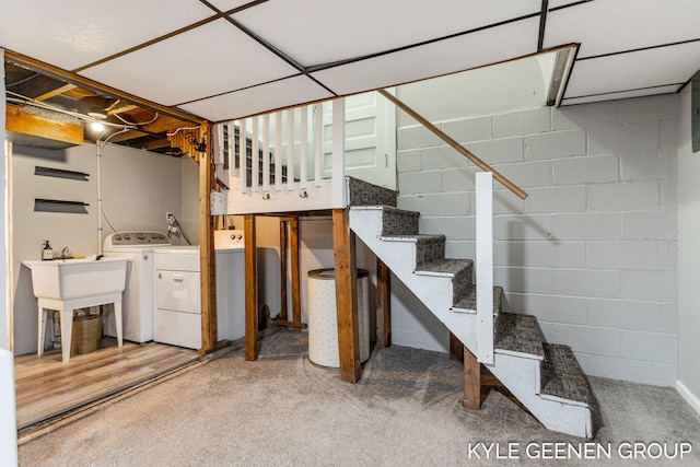 unfinished basement featuring stairway, independent washer and dryer, and concrete block wall