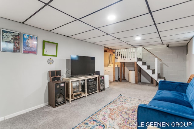 living room featuring a drop ceiling, washer / dryer, stairs, and carpet floors