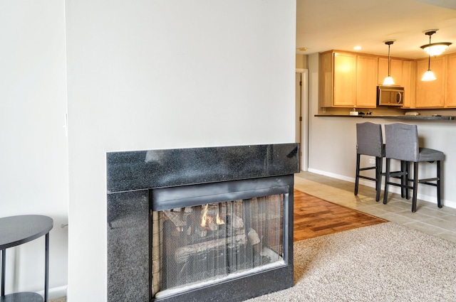 interior details featuring a tiled fireplace, stainless steel microwave, and baseboards