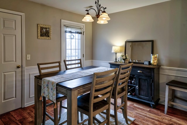 dining room with a notable chandelier, wainscoting, visible vents, and dark wood-style flooring