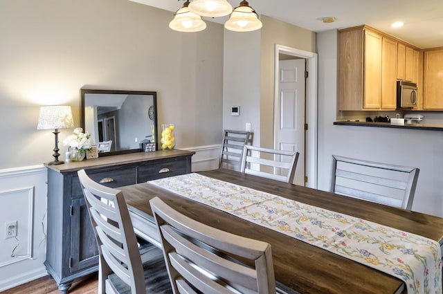 dining area featuring a decorative wall, recessed lighting, and a wainscoted wall