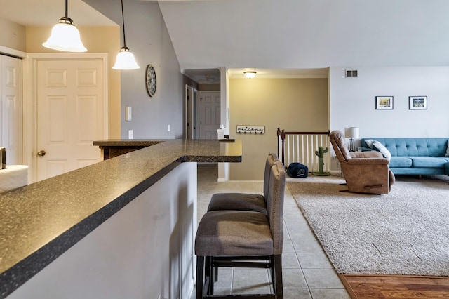 kitchen with dark countertops, visible vents, decorative light fixtures, open floor plan, and light tile patterned floors