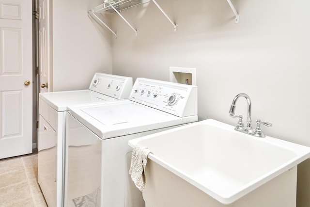 washroom featuring laundry area, washing machine and clothes dryer, light tile patterned flooring, and a sink