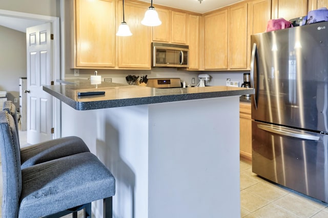 kitchen with light brown cabinetry, light tile patterned floors, appliances with stainless steel finishes, and a peninsula