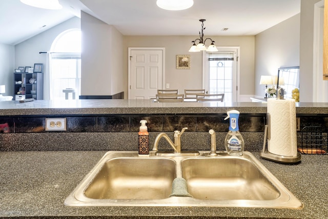 kitchen featuring vaulted ceiling, a notable chandelier, a healthy amount of sunlight, and a sink