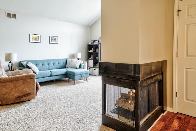 living room with visible vents, lofted ceiling, and carpet floors