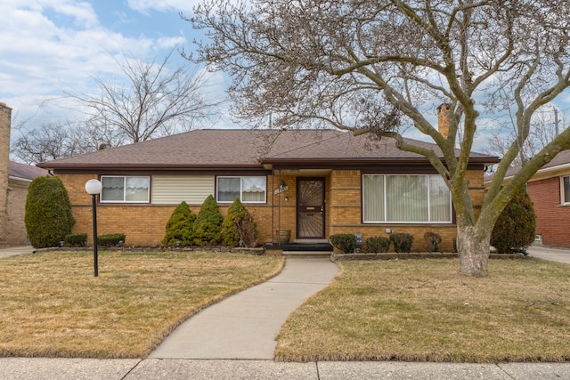 ranch-style house featuring brick siding, a shingled roof, and a front lawn