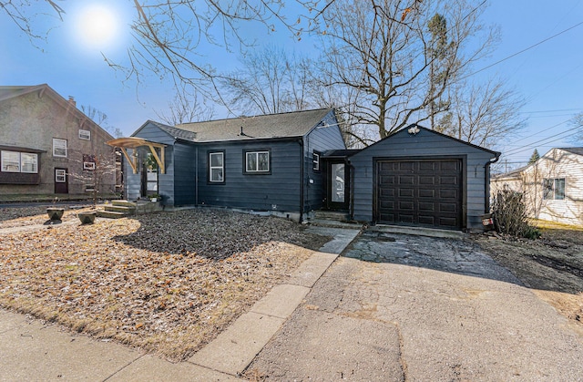 view of front facade featuring aphalt driveway, a detached garage, and roof with shingles