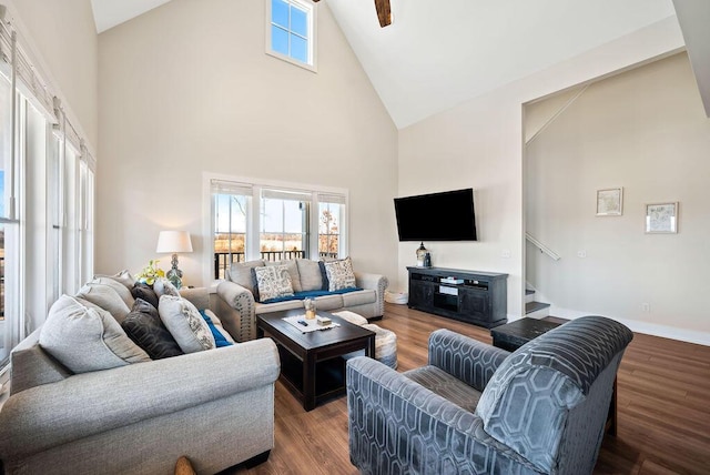 living room featuring a wealth of natural light, high vaulted ceiling, baseboards, and wood finished floors