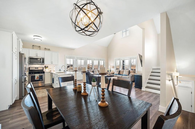 dining space with dark wood finished floors, an inviting chandelier, stairs, and high vaulted ceiling