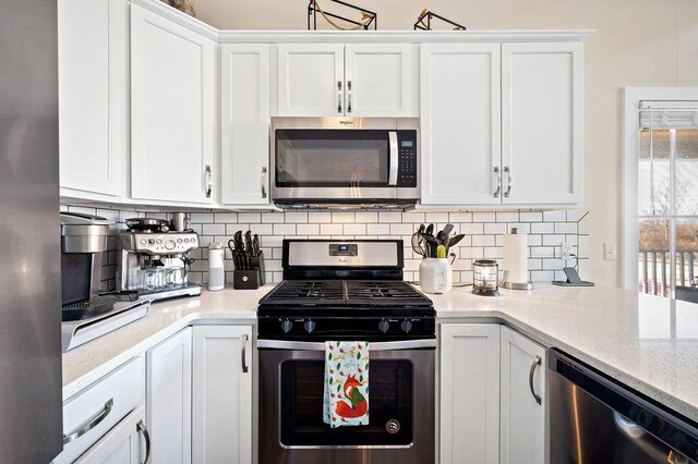 kitchen featuring white cabinetry, light stone countertops, tasteful backsplash, and appliances with stainless steel finishes