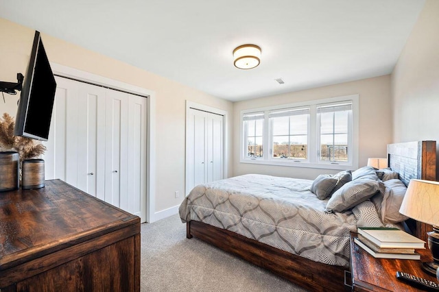 carpeted bedroom with baseboards and two closets