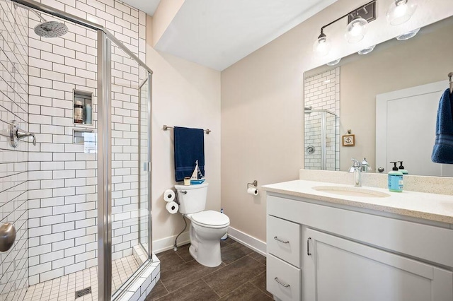 bathroom featuring a shower stall, toilet, vanity, and baseboards