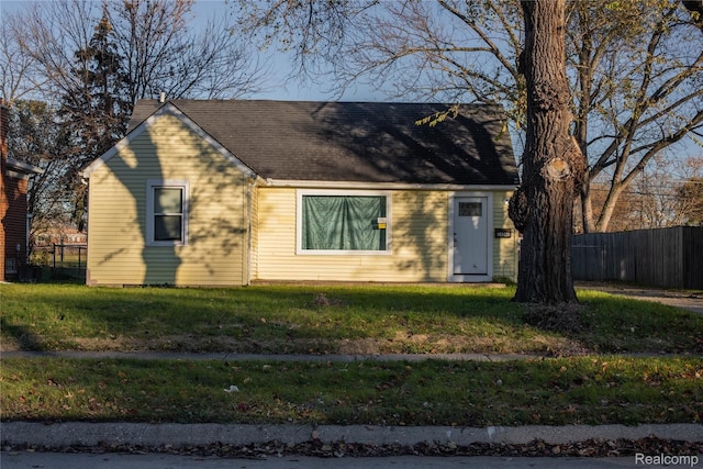 cape cod house with a front yard and fence