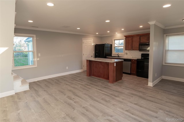 kitchen with black appliances, tasteful backsplash, a wealth of natural light, and a kitchen island