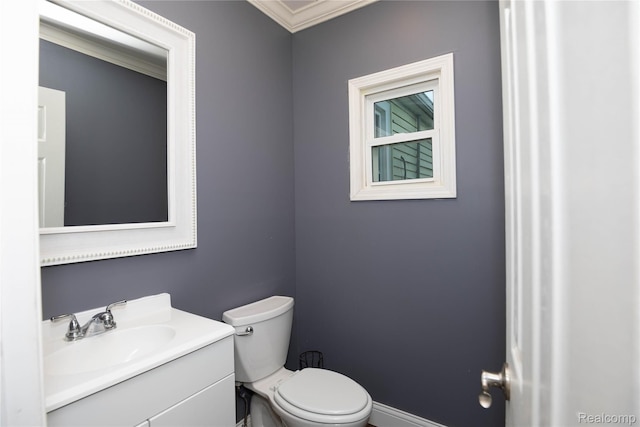 half bathroom featuring baseboards, toilet, ornamental molding, and vanity