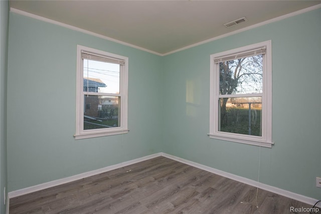 spare room featuring baseboards, plenty of natural light, dark wood-style flooring, and crown molding