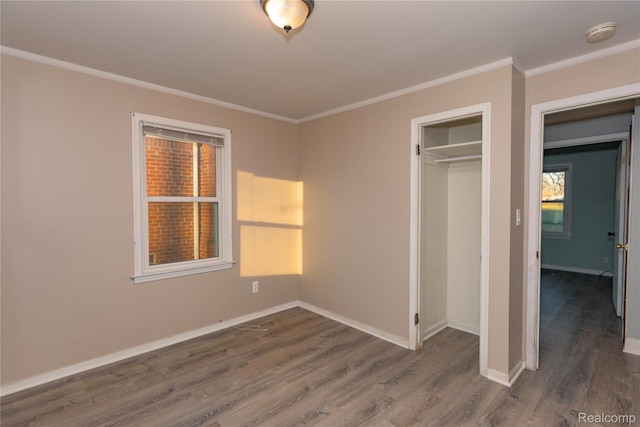 unfurnished bedroom featuring a closet, baseboards, wood finished floors, and ornamental molding