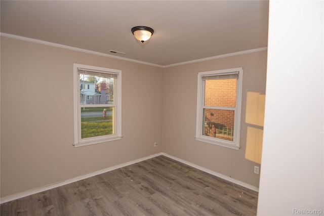 spare room featuring visible vents, crown molding, baseboards, and wood finished floors