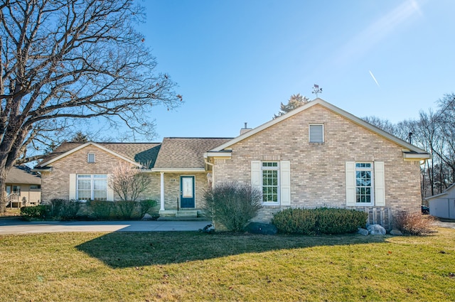 view of front of property with brick siding, a chimney, a front yard, and roof with shingles